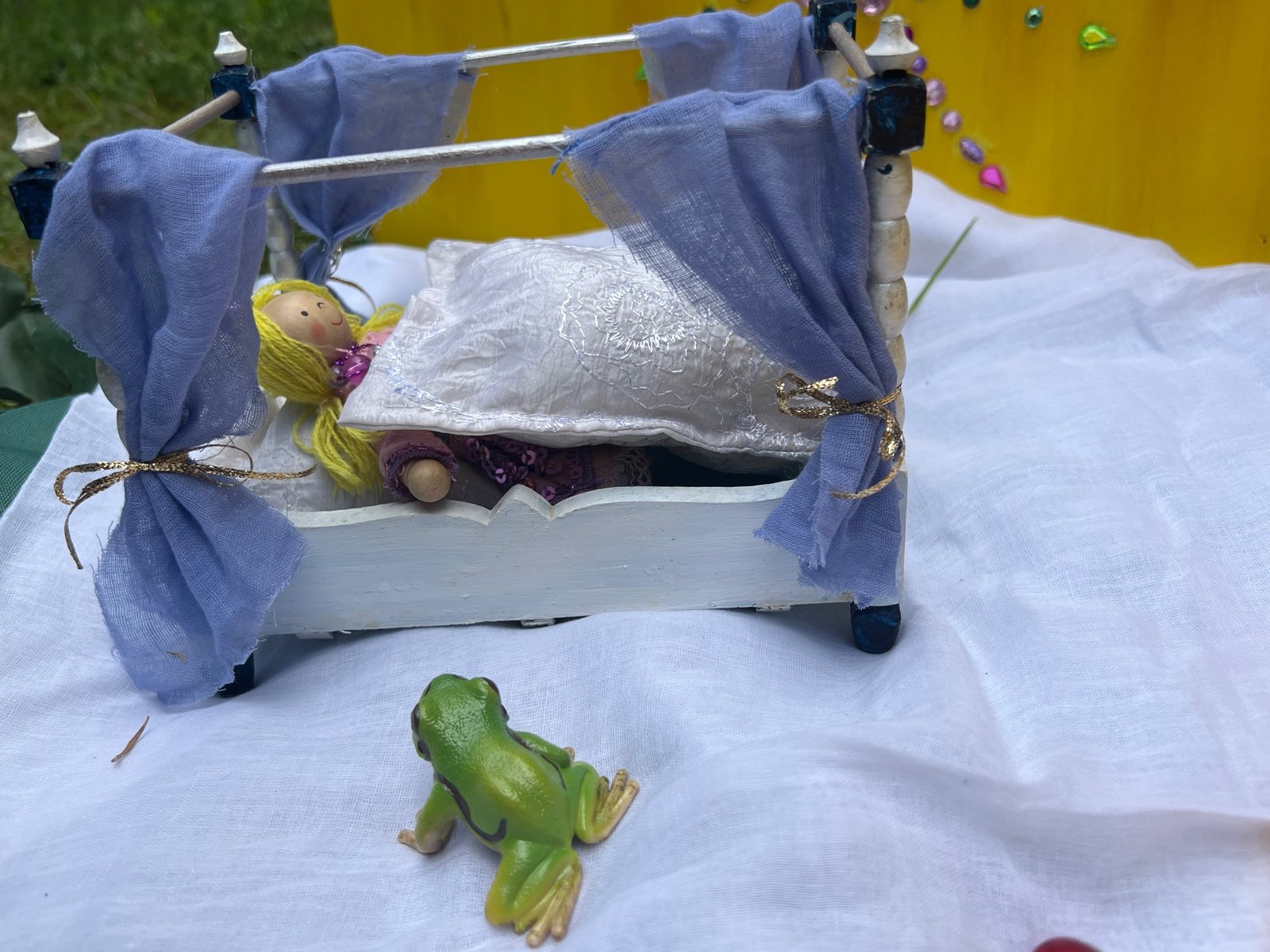 Spielszene zum Froschkönig: die Prinzessin liegt in einem Himmelbett mit blauen Vorhängen, davor sitzt der Frosch