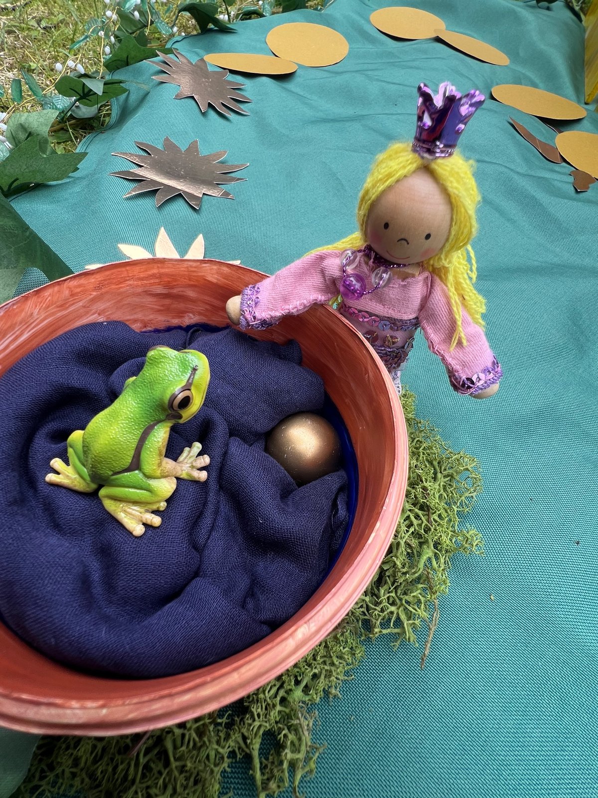 Spielszene zum Froschkönig: eine Prinzessin aus Holz beugt sich über den Brunnen, darin sitzen ein Frosch und die goldene Kugel